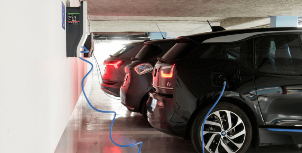 Véhicules électriques en stationnement, branchés à des bornes de recharge, symbolisant la transition vers la mobilité durable