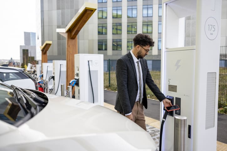 Un professionnel rechargeant un véhicule électrique sur une borne publique adaptée aux usages commerciaux